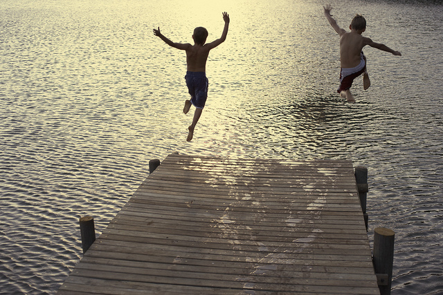 Two Boys Diving off Dock into Lake --- Image by © Royalty-Free/Corbis